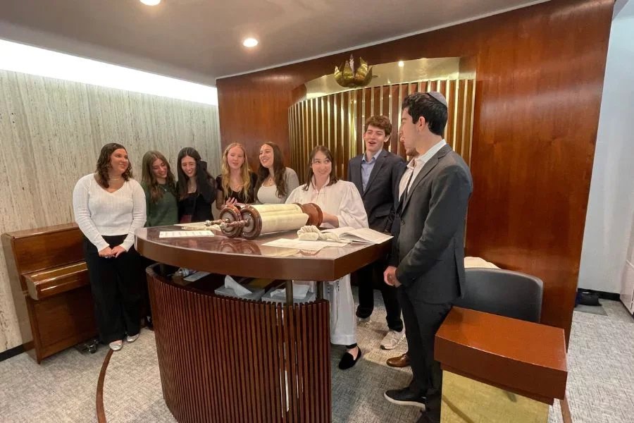teens with rabbi gathered around the torah