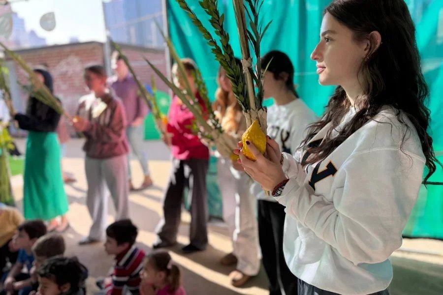teens shaking the lulav and etrog in sukkah