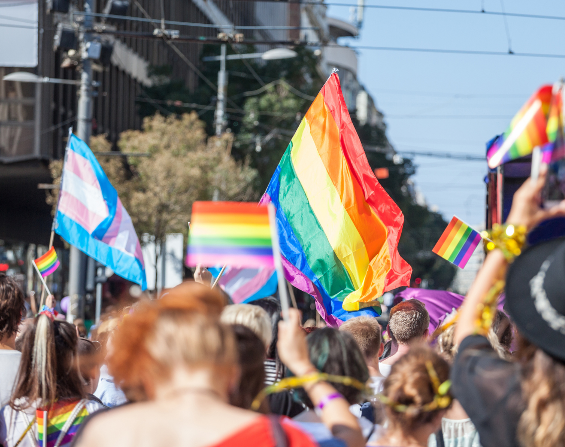 photo of gay pride parade taken looking forward at flags flying as people march