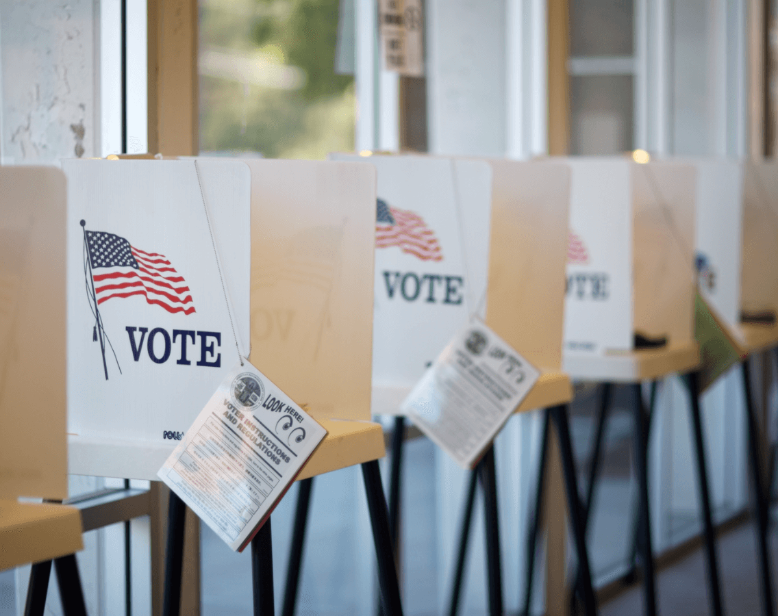 voting booths, each with a poster on the side with the american flag and the word vote