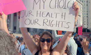woman holding up a sign that says my choice our health our rights at a reproductive rights march