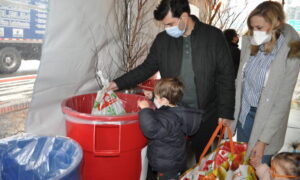 MLK Day of service - parents with two young children dropping off needed donations in the tent on 79th street